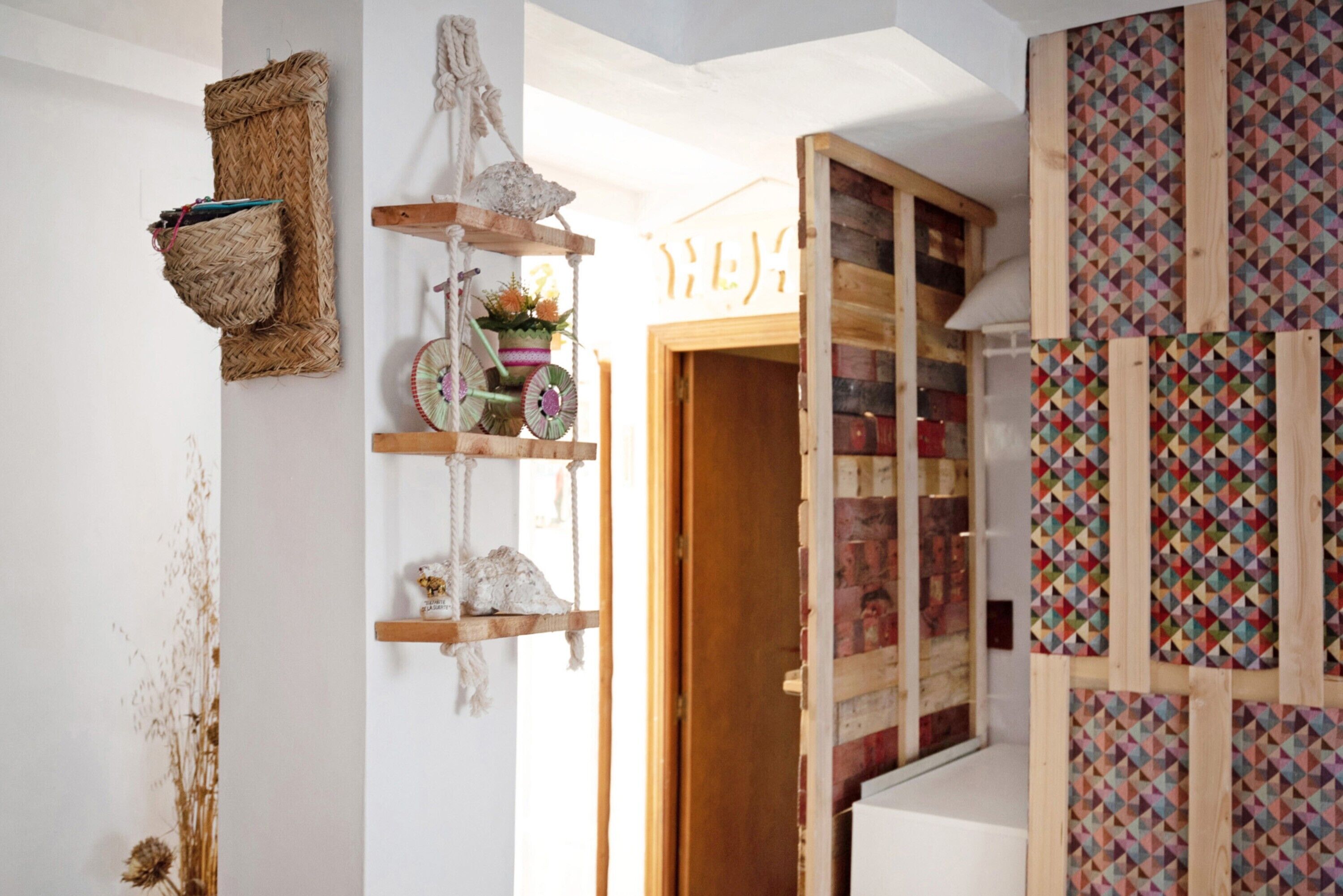 Een kamer met een houten trap, een wandplank met decoratieve objecten en een wandpaneel met patroon.