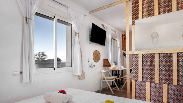 A bedroom with two beds, a TV, a desk, and a patterned wall. - Apartment "Casa Chipiron" with Mountain View, Terrace & Wi-Fi (Vejer de la Frontera)