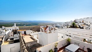 A rooftop terrace with a table and chairs, white buildings, and a distant view of the landscape. - Apartment "Casa Chipiron" with Mountain View, Terrace & Wi-Fi (Vejer de la Frontera)