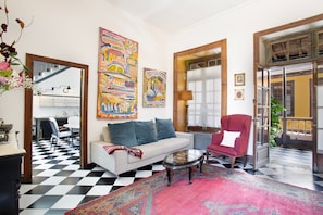 A living room with a checkered floor, a sofa, a red armchair, a coffee table, and two large paintings. - "Casa Montesdeoca - Tamarindo" with Balcony & Wi-Fi (Las Palmas de Gran Canaria)