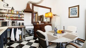 Eine Küche mit Schachbrettboden, einem Esstisch mit Platzsets, einer Lampe und einer Obstschale.