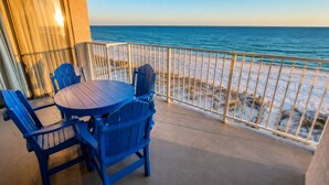A balcony with a table and chairs overlooking a beach. - Shoreline Towers (Gulf Shores)