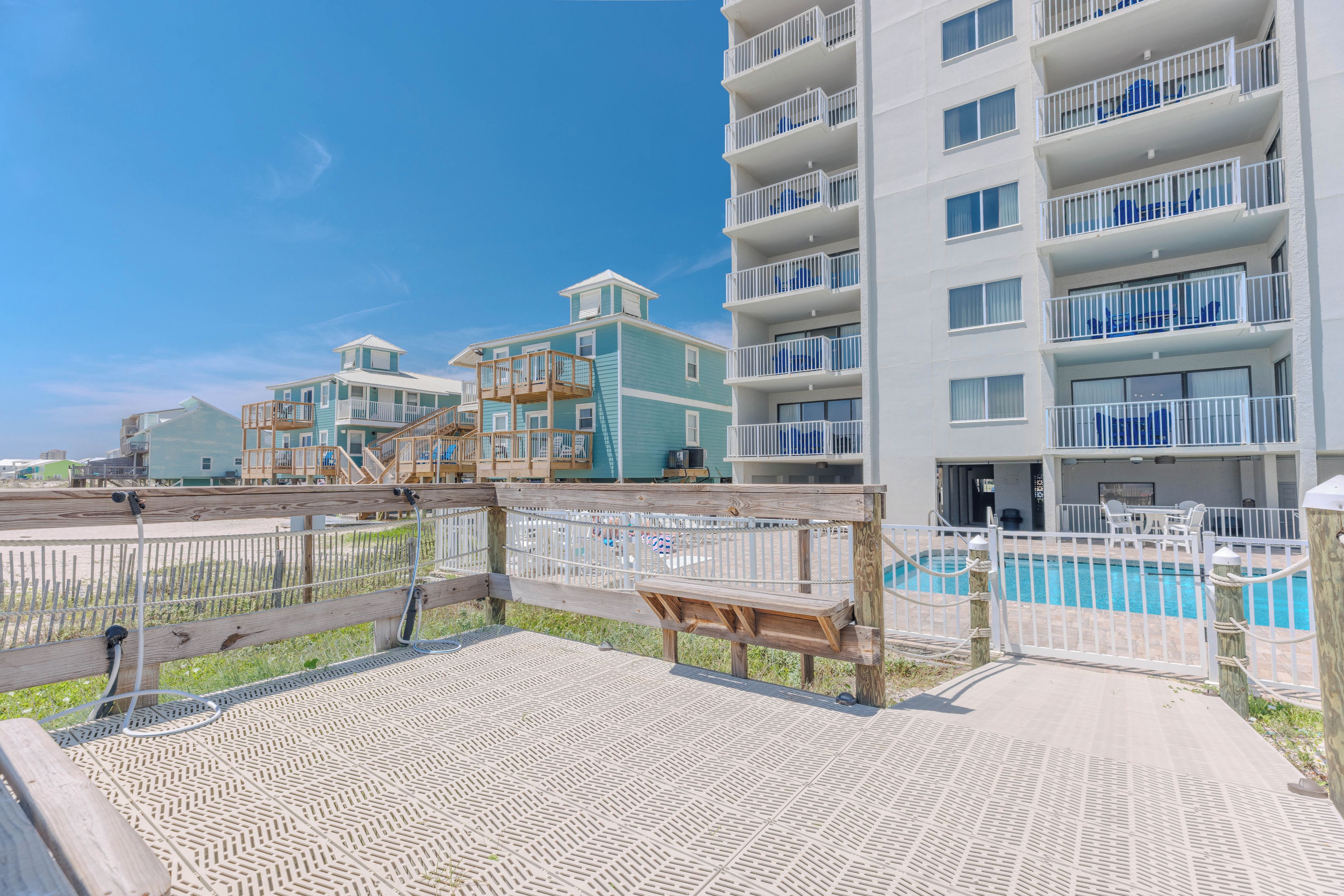 A beachfront hotel with multiple balconies, a pool, and a wooden deck area.