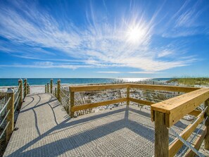 A wooden boardwalk leading to a beach with a clear sky. - Shoreline Towers (Gulf Shores)