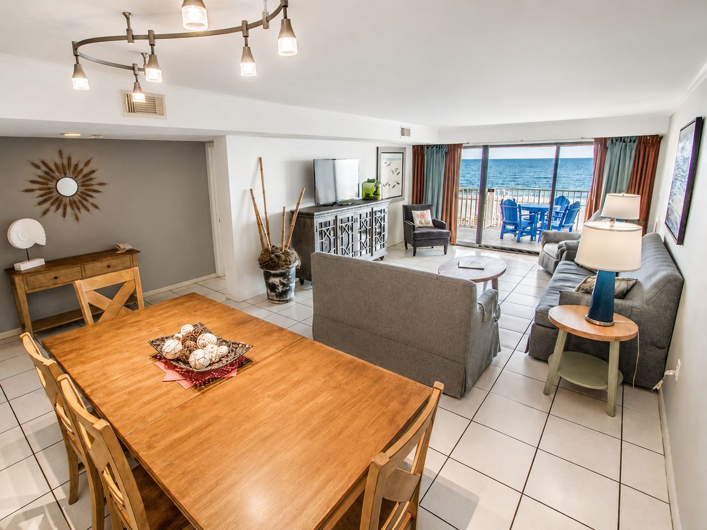Ein modernes Wohnzimmer mit einem Holzesstisch, einem grauen Sofa und Blick auf das Meer.