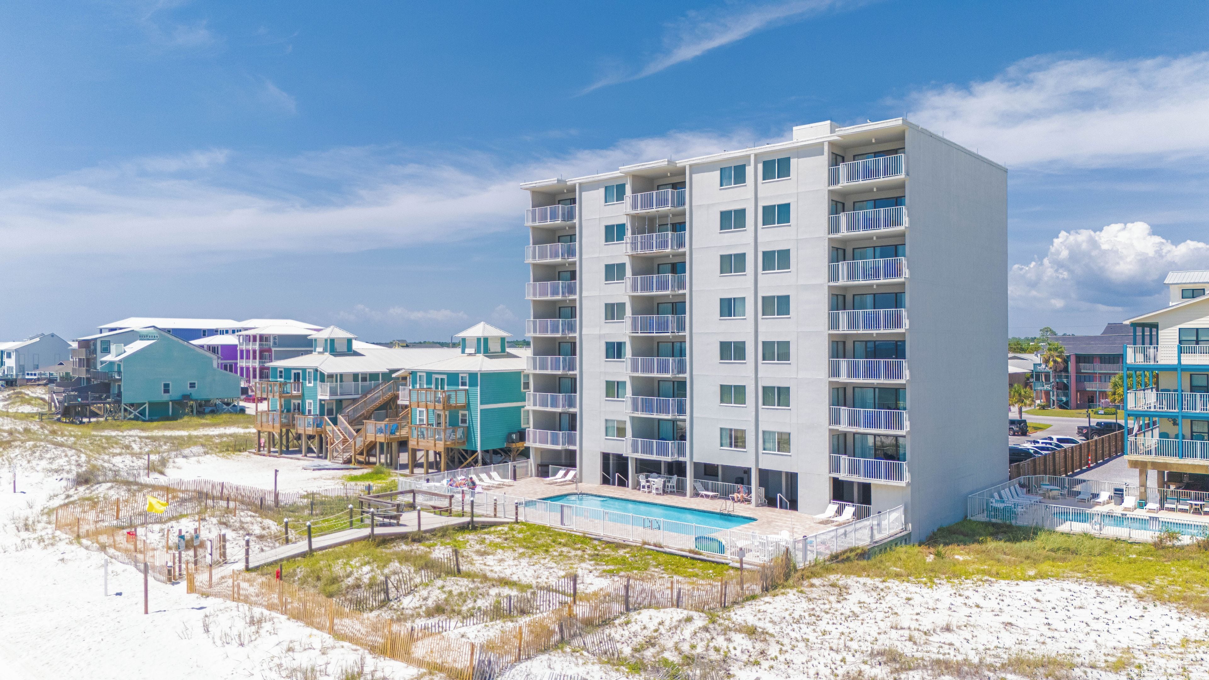 Un hôtel à plusieurs étages doté de balcons, d’une piscine et d’un accès à la plage.