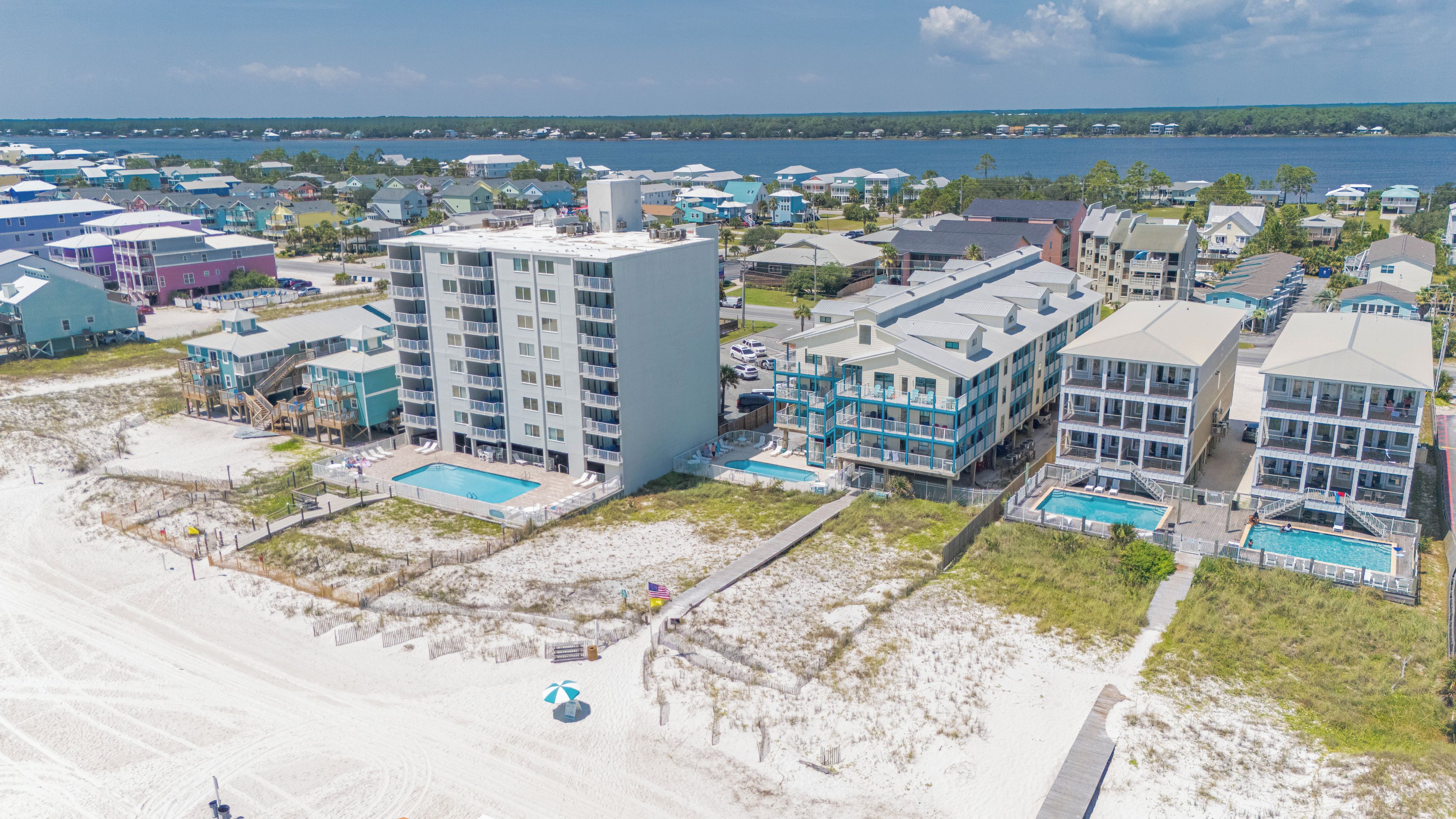 A coastal hotel with multiple buildings, a swimming pool, and a beach area.