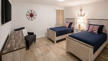 Une chambre d’hôtel avec deux lits en bois, un bureau, une chaise, une télévision et une décoration murale représentant une boussole.