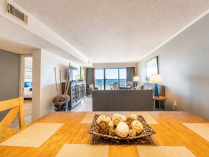 A hotel room with a dining area, a balcony with a view, and a reception desk. - Shoreline Towers (Gulf Shores)