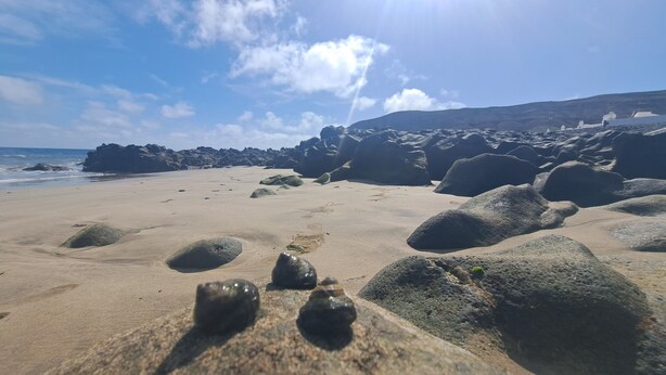 Una spiaggia con grandi rocce e un cielo sereno.