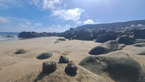 A beach with large rocks and a clear sky.