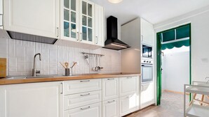 Una cucina con mobili bianchi, un lavello in acciaio inox e una cappa aspirante nera.