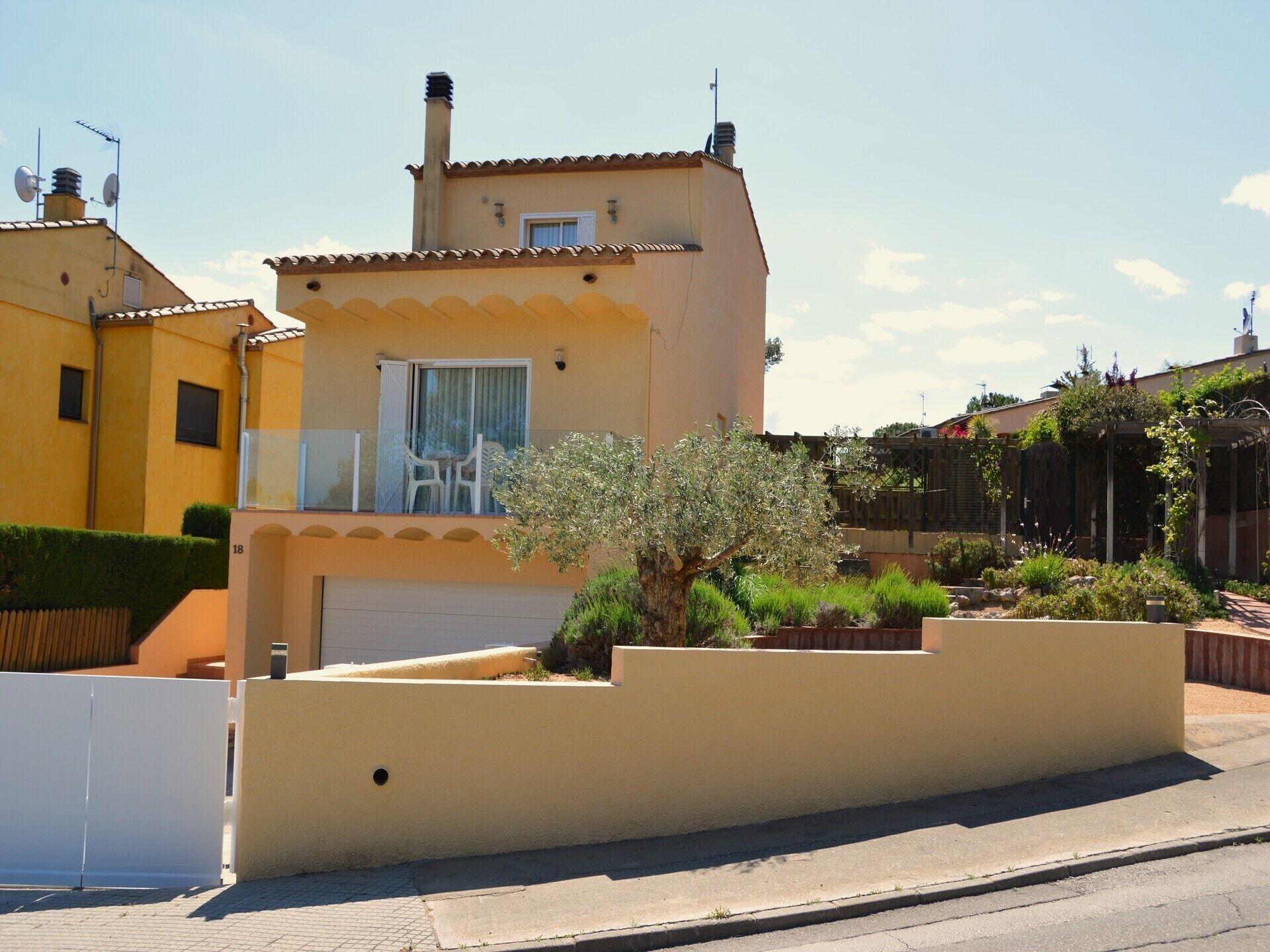 A residential building with a balcony, a garage, and a garden area.