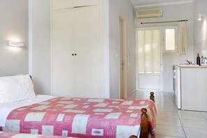 Une chambre comprenant un lit, une table de chevet, une armoire, un coin cuisine et une salle de bain.