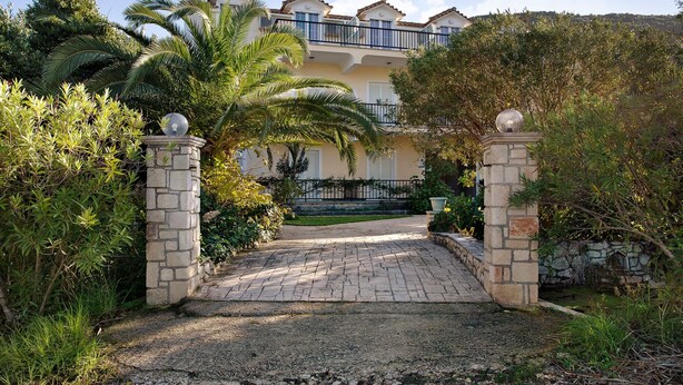A building with a stone entrance, a paved pathway, and a balcony. - Apartment "Dolphin Apartment 1" with Private Balcony, Shared Garden & Wi-Fi (Zakynthos)