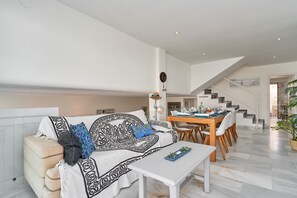 Un salon moderne avec un canapé, une table à manger et un escalier.