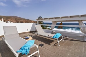 A rooftop terrace with two sun loungers, a small table with a book and glass, and a view of the ocean. - Holiday Home "Casa Sueña" Near the Beach with 4 Private Terraces (Calahonda  (Granada))