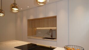 A modern kitchen with a black induction cooktop, wooden cabinets, and a marble countertop. - Holiday Home "Casa Sueña" Near the Beach with 4 Private Terraces (Calahonda  (Granada))