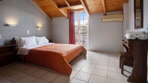 A bedroom with a bed, wooden ceiling beams, an air conditioning unit, a window with a view, and a wooden dresser.