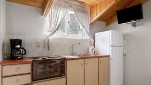 A kitchen with wooden cabinets, a built-in oven, a refrigerator, a sink, and a window with curtains.