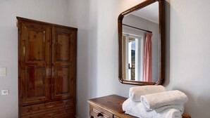 Une armoire en bois, un miroir et une pile de serviettes blanches posées sur une commode en bois.