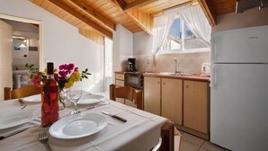 Eine Küche mit Holzausstattung, einem Kühlschrank, einer Spüle und einem Fenster mit Vorhängen.