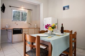Un coin repas avec une table dressée pour quatre personnes, un four à micro-ondes, une machine à café et un réfrigérateur.