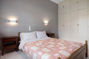 Une chambre à coucher comprenant un lit, deux tables de chevet, une armoire et des lampes fixées au mur.
