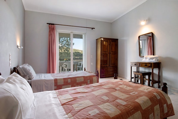 A bedroom with two beds, a wooden wardrobe, a desk with a mirror, and a view of the outdoors through a sliding door. - Apartment "Dolphin Apartment 8" with Private Balcony, Shared Garden & Wi-Fi (Zakynthos)