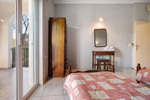Una camera da letto con un letto, un armadio in legno, un comodino con specchio e una porta che dà su un balcone.