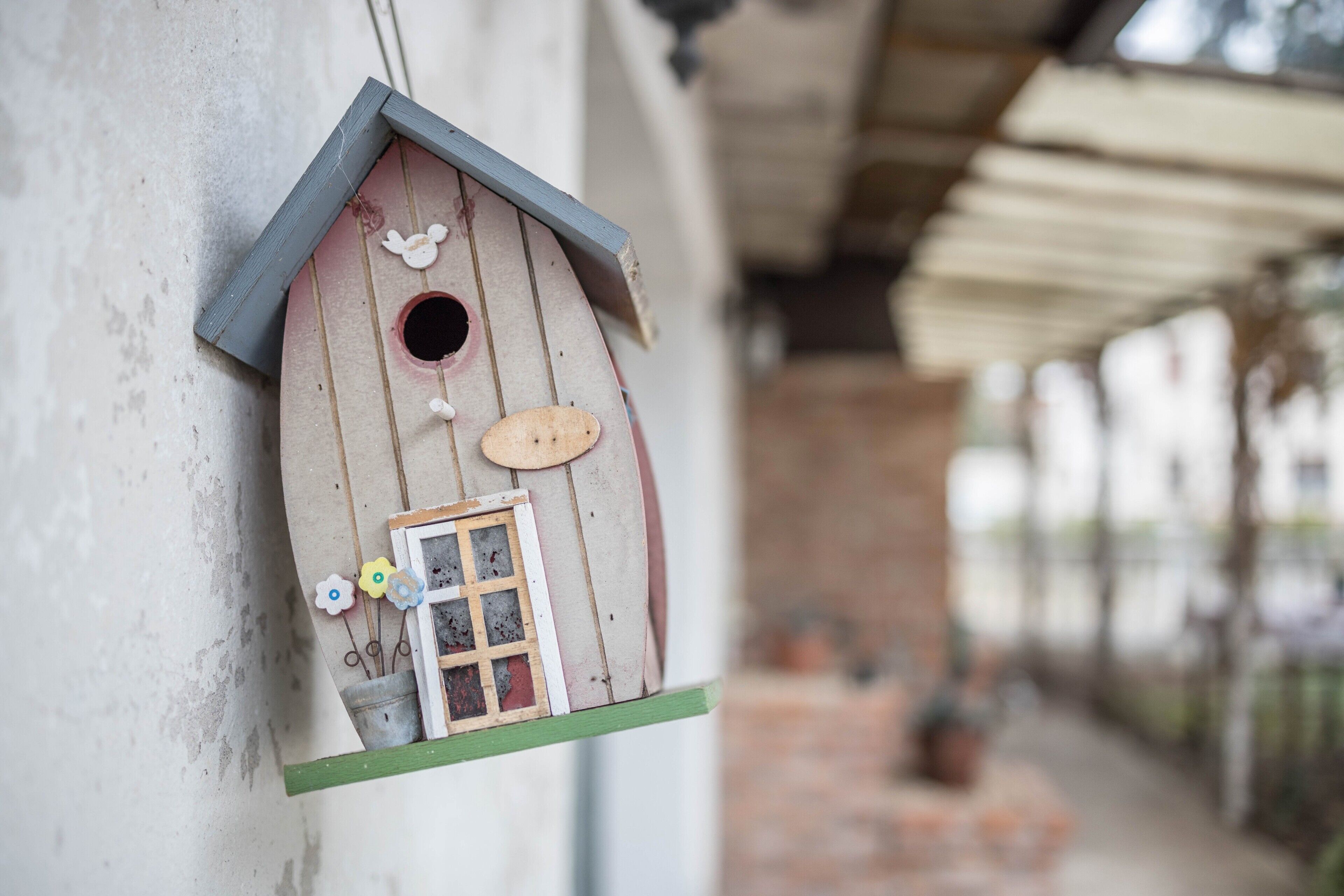 A birdhouse attached to a wall with a window and a small door.