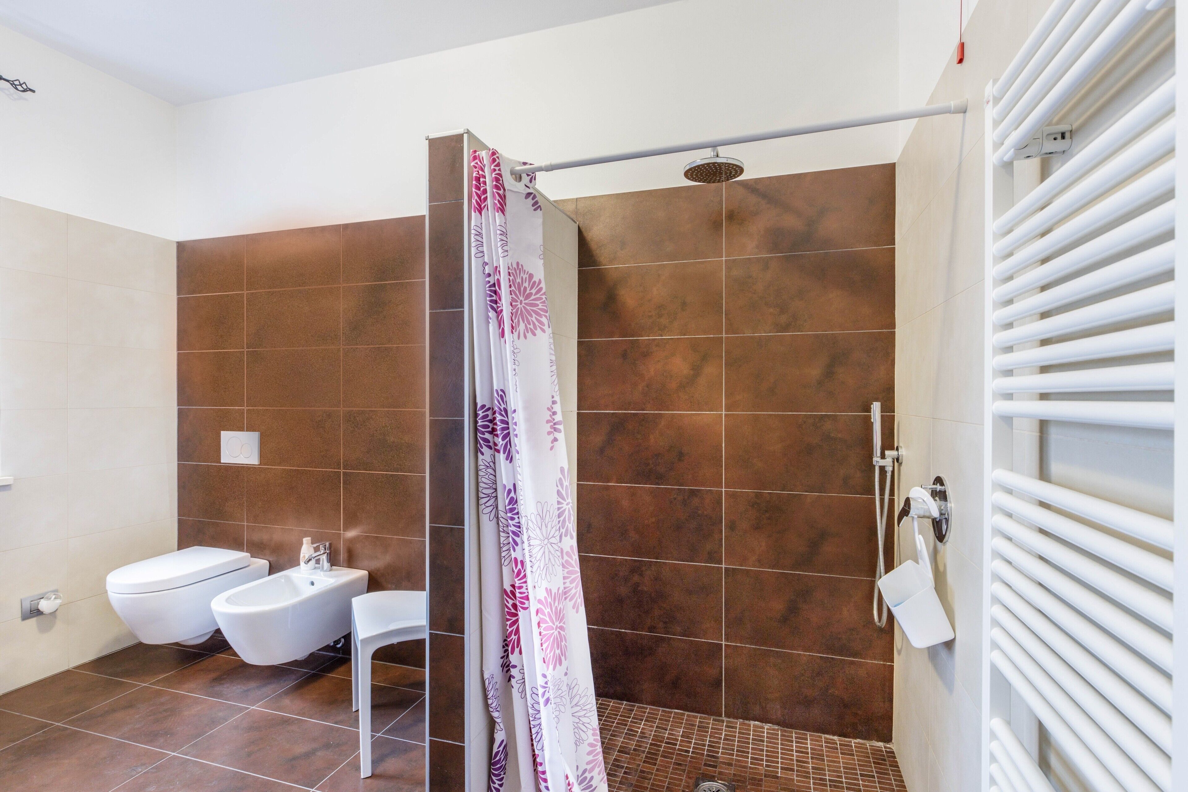 Une salle de bain moderne équipée d’une douche, d’un bidet et d’un porte-serviettes blanc.
