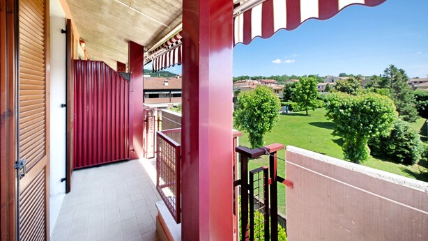 Ein Balkon mit Blick auf eine grüne Landschaft und Gebäude.