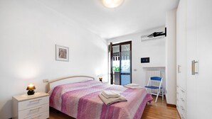 Ein Schlafzimmer mit Bett, Nachttisch, Lampe, Stuhl und Kleiderschrank.