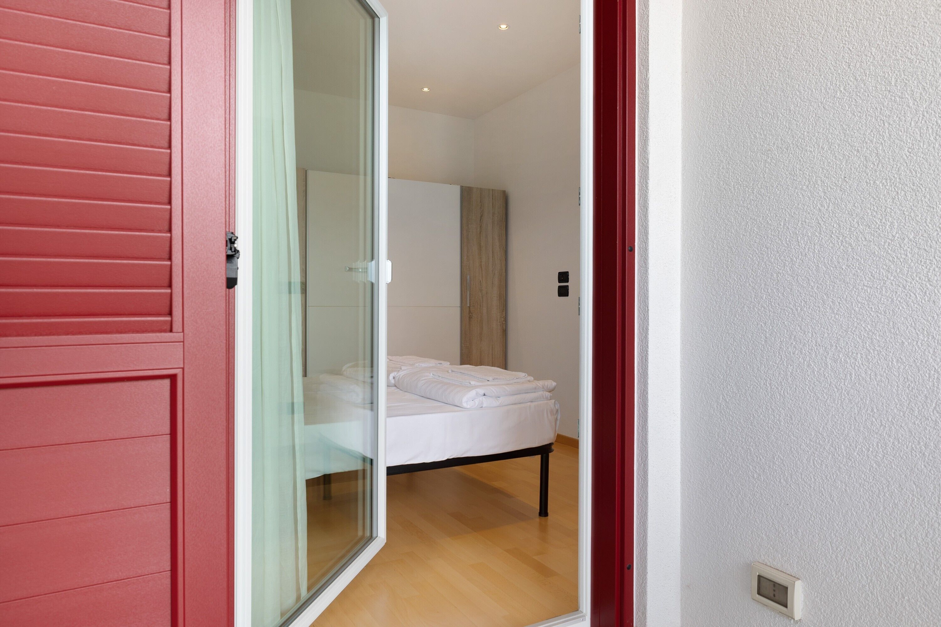 Een kamer met een bed, een glazen schuifdeur en een rode wand.
