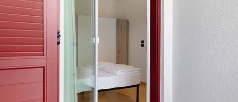 Een kamer met een bed, een glazen schuifdeur en een rode wand.