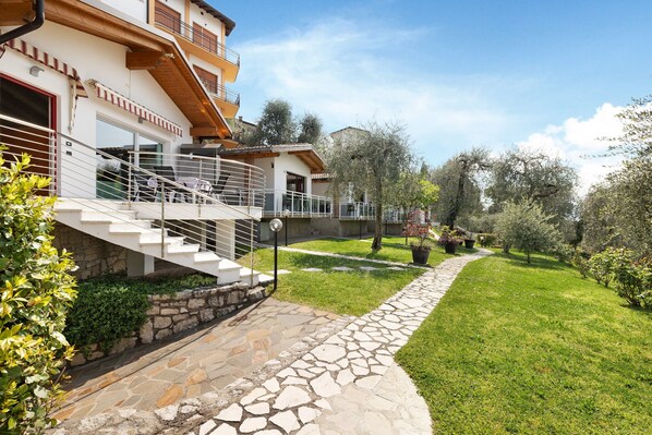 A multi-story residential building with a stone pathway leading to a grassy area.