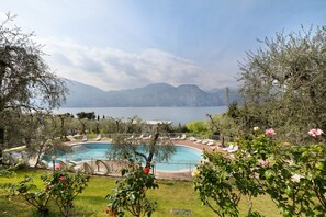 Una piscina con sillones de descanso, rodeada de vegetación y con montañas al fondo.