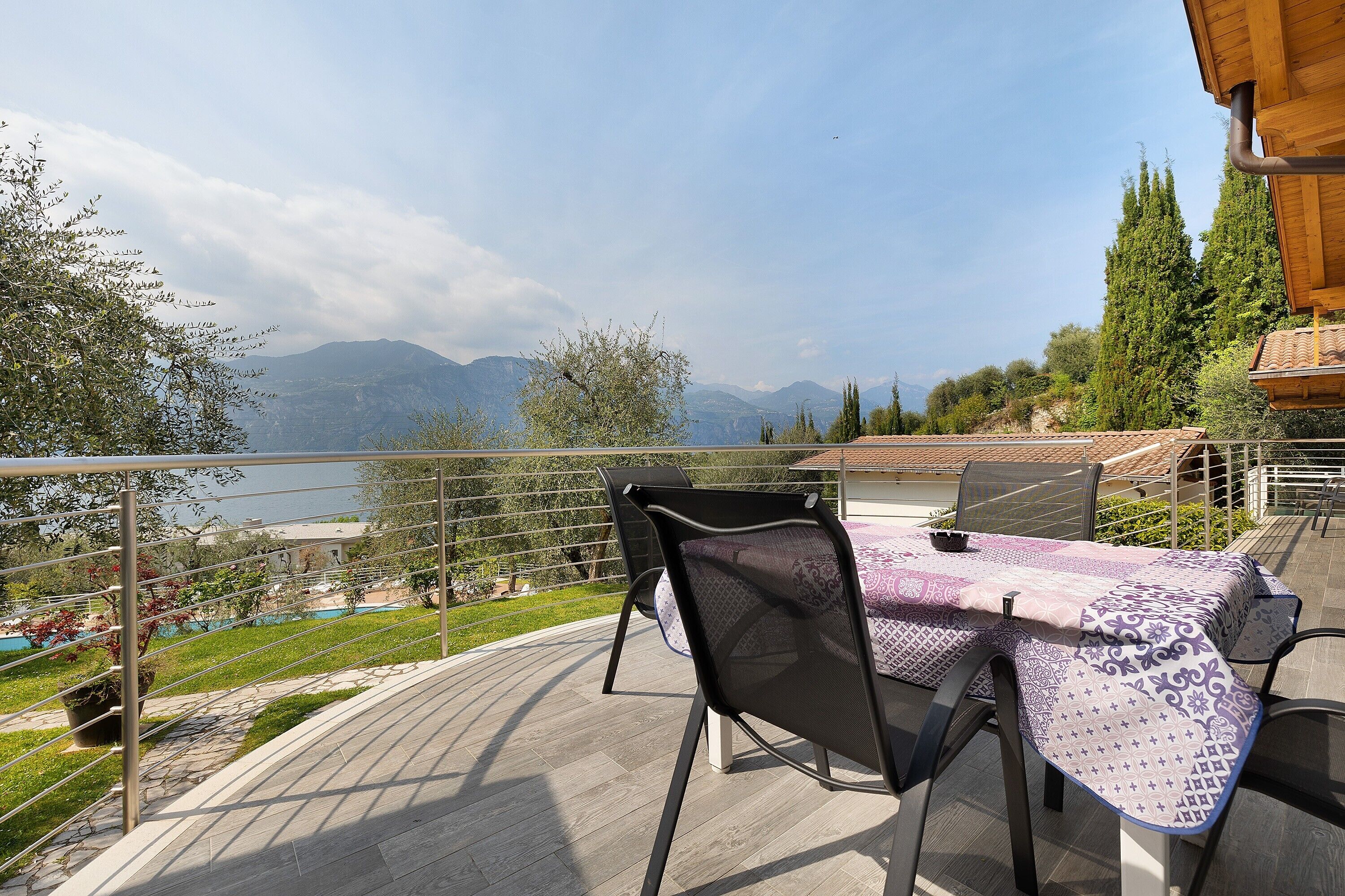 A terrace with a table and chairs, overlooking a mountainous landscape.