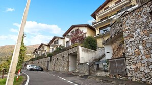 Une rue bordée d’immeubles en pierre, un fourgon blanc et une voiture garée.