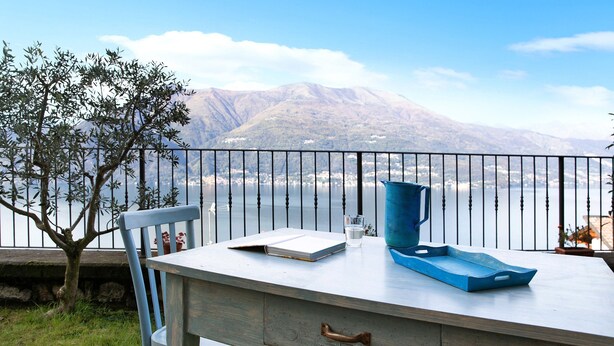 Une table avec un carnet, un verre et un plateau bleu, le tout placé devant un paysage montagneux pittoresque.