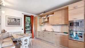 Une cuisine moderne avec des meubles en bois, un four à micro-ondes encastré et un coin repas comprenant une table et des chaises.