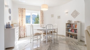 A dining area with a white table, chairs, and a hanging light fixture. - "Villa with private swimming pool" with Sea View, Private Terrace & Wi-Fi (Mijas Pueblo)