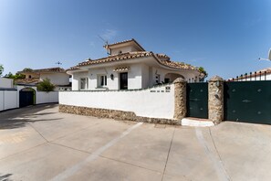 A house with a tiled roof, a white exterior, and a gated entrance.