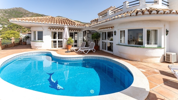 A poolside area with a swimming pool, sun loungers, and a white building with a tiled roof. - "Villa with private swimming pool" with Sea View, Private Terrace & Wi-Fi (Mijas Pueblo)