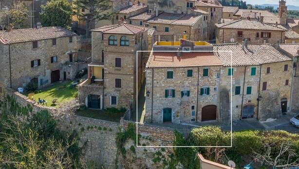 Un edificio histórico de piedra con numerosas ventanas, un patio interior y vistas del pueblo circundante.