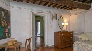 Una habitación con una cama, un aparador de madera, una silla, una mesa con un control remoto y un cuadro en la pared.