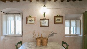 Un comedor con una mesa de mármol, dos cestos de mimbre, sillas verdes y cuadros en la pared.