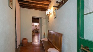 Un pasillo con un banco de madera, una puerta verde y un piso de baldosas.