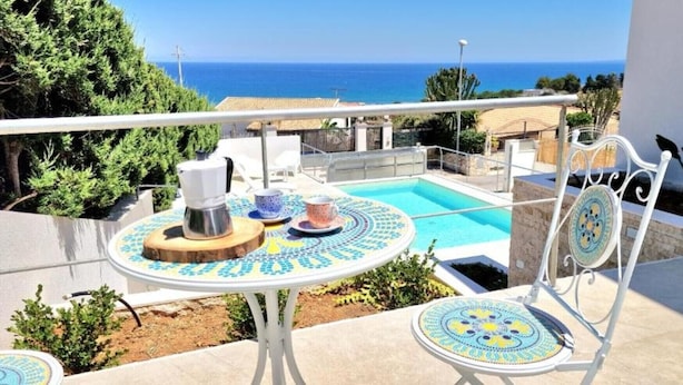 Un balcone con piscina, mobili da esterno e vista sul mare.